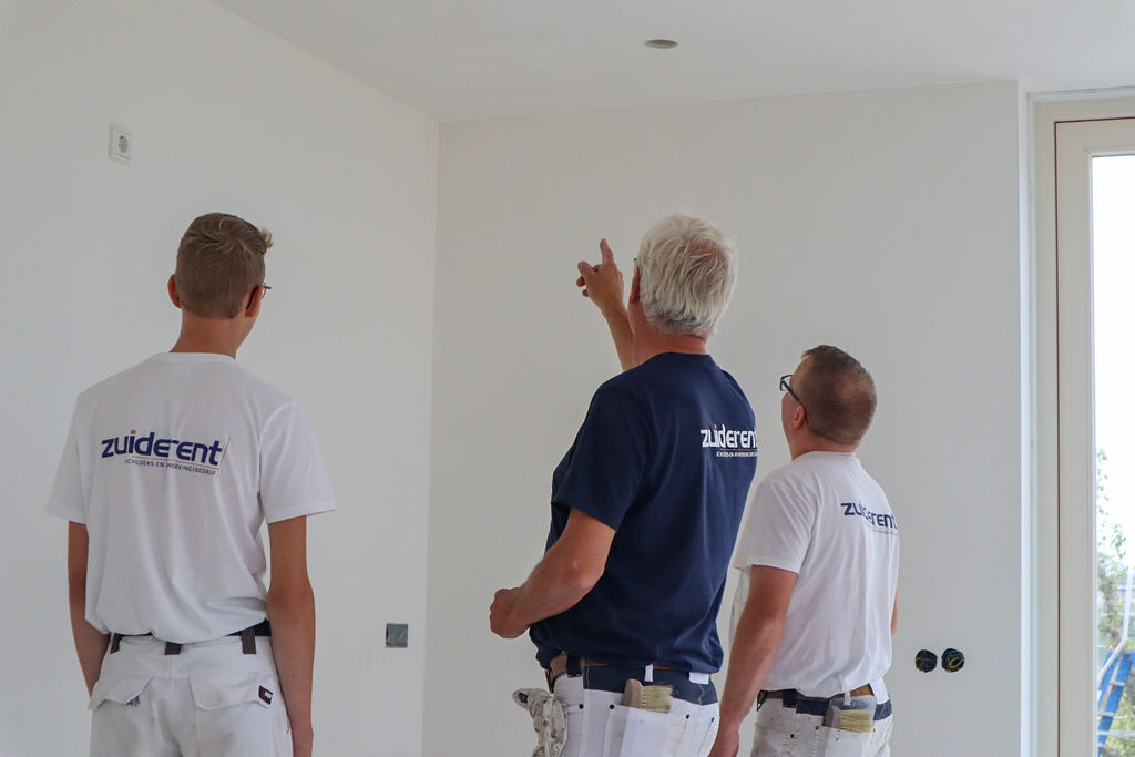 Drie schilders overleggen over de schilder werkzaamheden op locatie