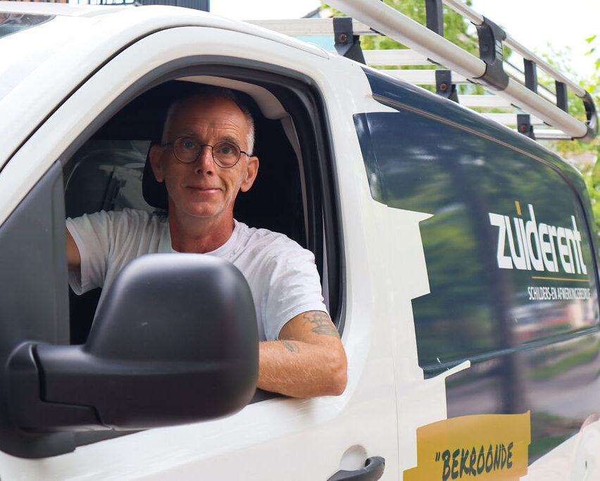 Medewerker Zuiderent zit in werkbus en lacht